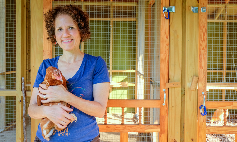 Michelle holding chicken in front of chicken coop.