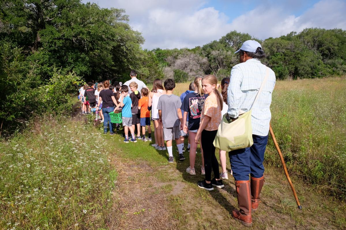 Students and teacher walking on a trail in nature.