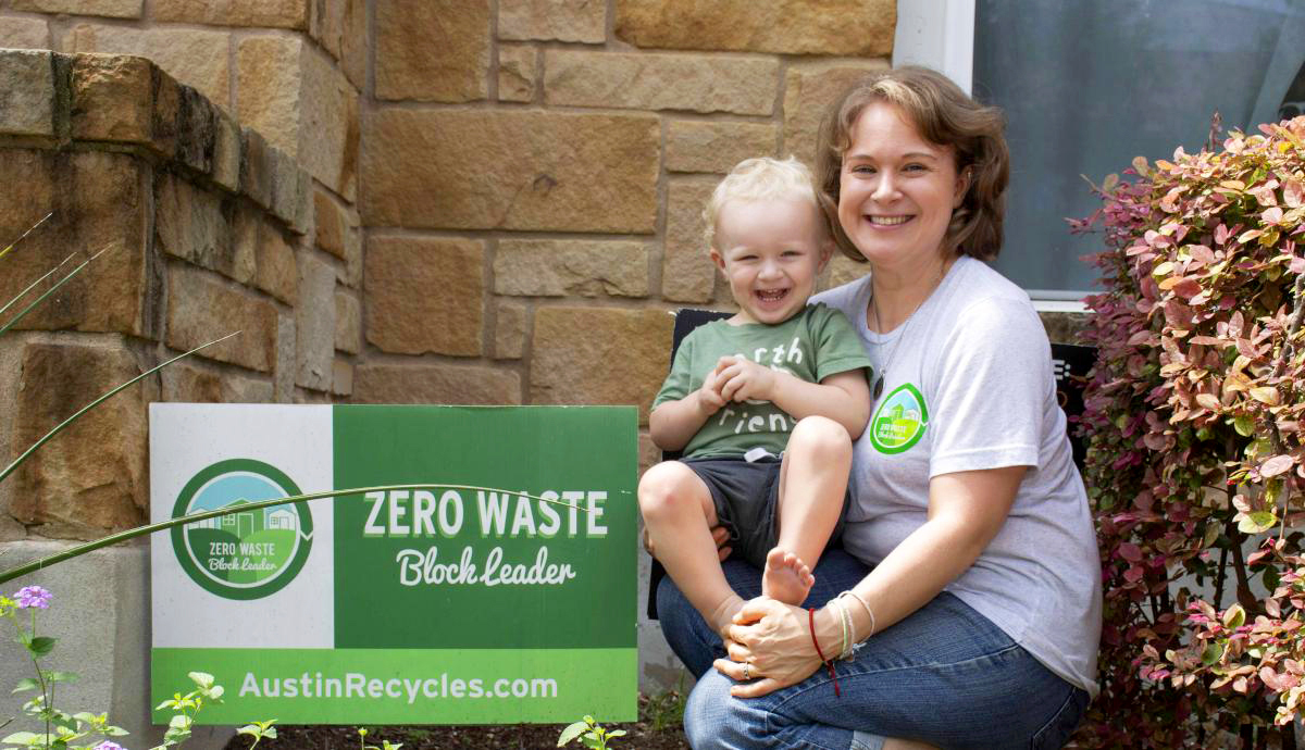 Taylor with her son outside of her home next to a sign that reads "Zero Waste Block Leader austinrecycles.com"