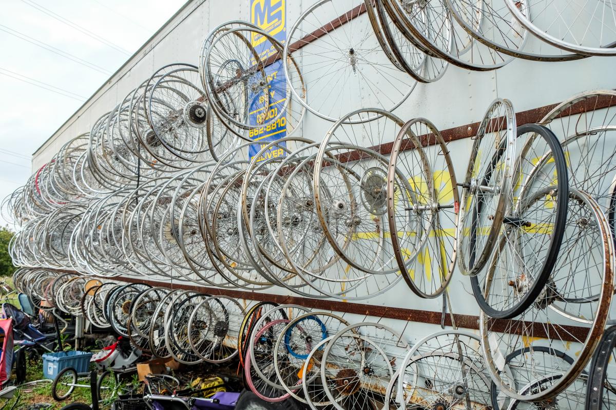 Bicycle wheels all hung up on the side of a trailer outside on a grey day.